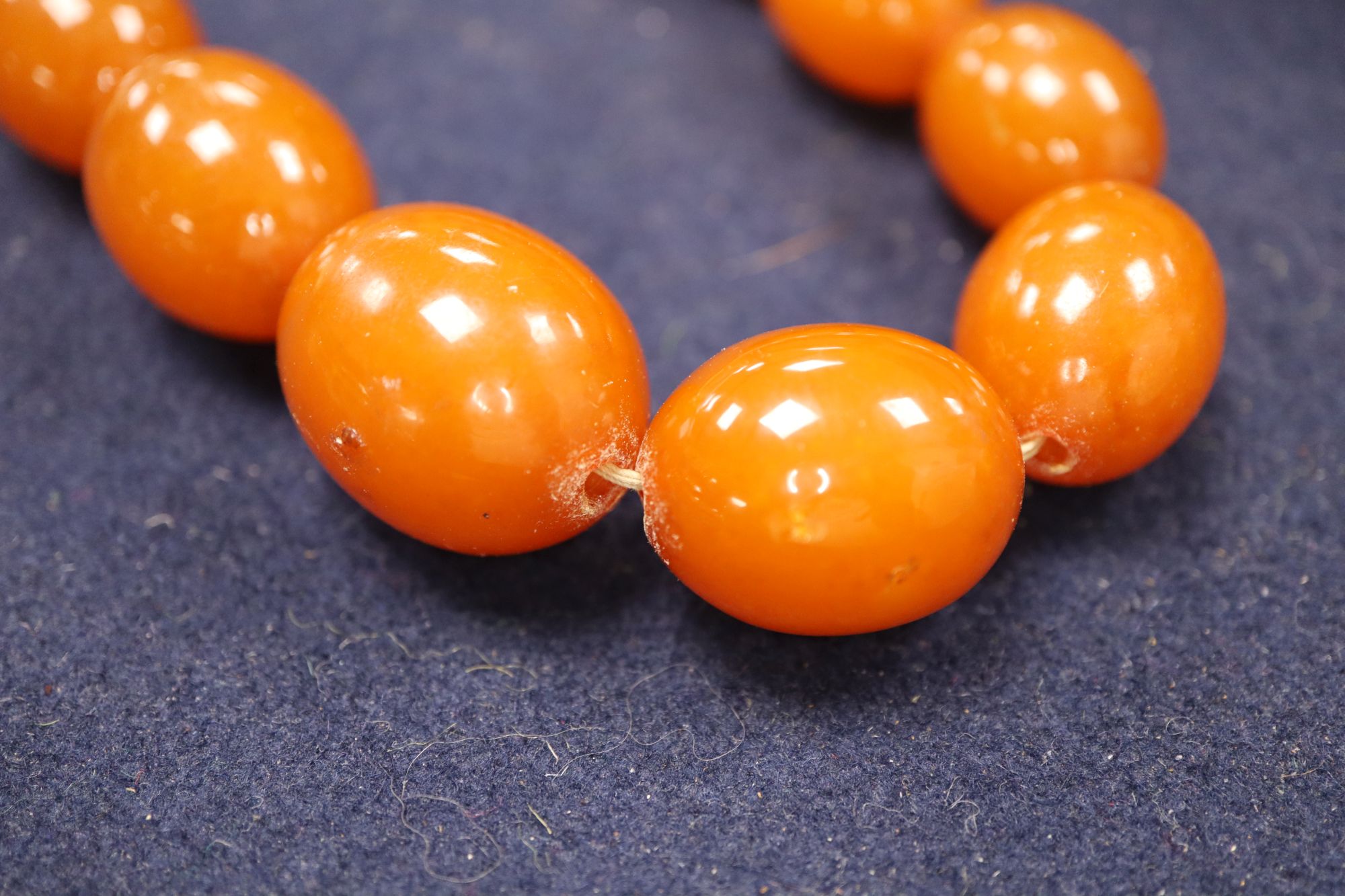 An amber necklace(a.f.) gross 85 grams, four assorted amber pebbles, 528 grams, a carved amber pendant